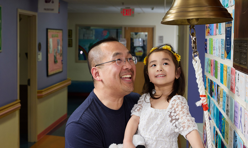 Mikaela and her dad, Jon, share a special bell-ringing moment to celebrate her remission.