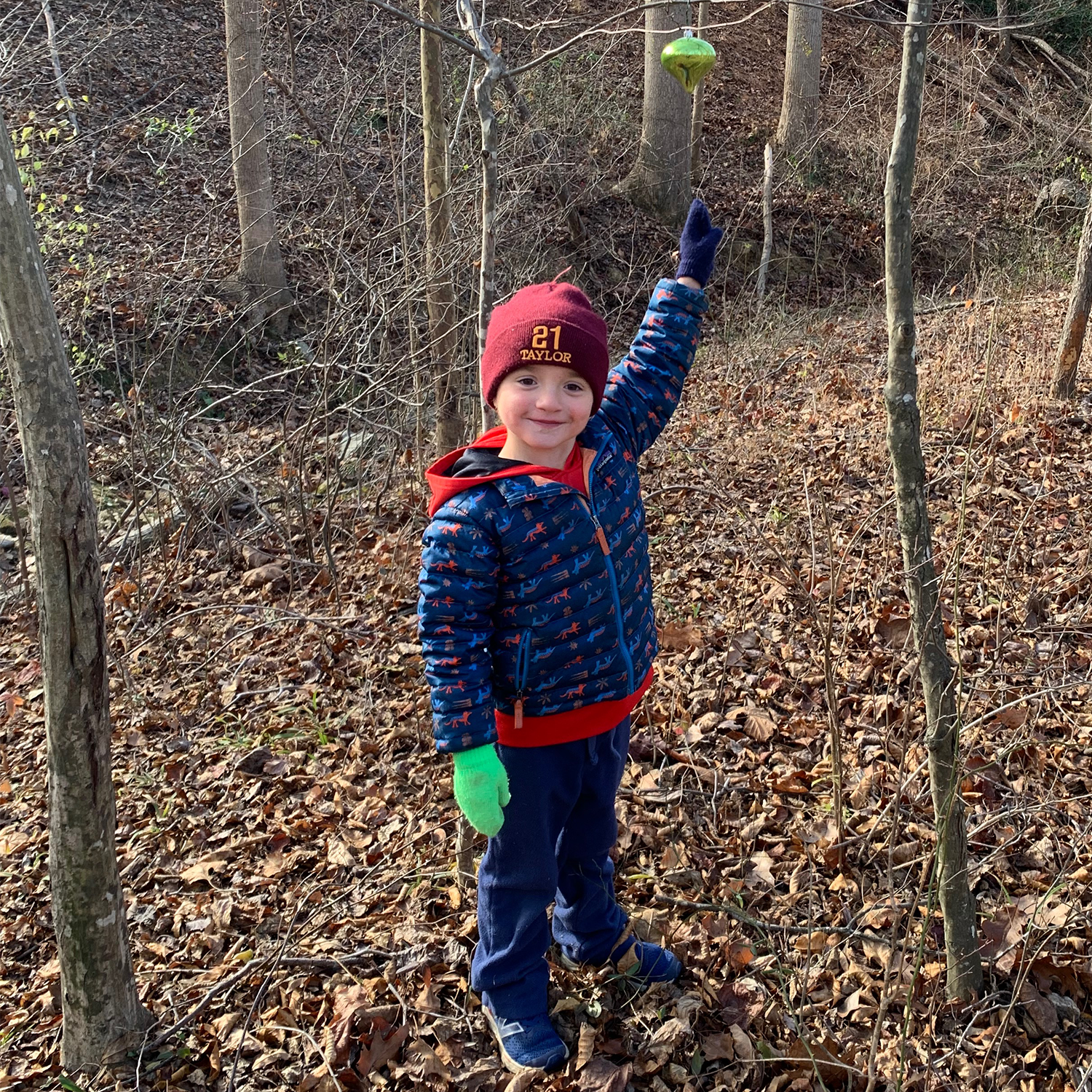 John in warm clothing and a beanie outside showing a bird feeder