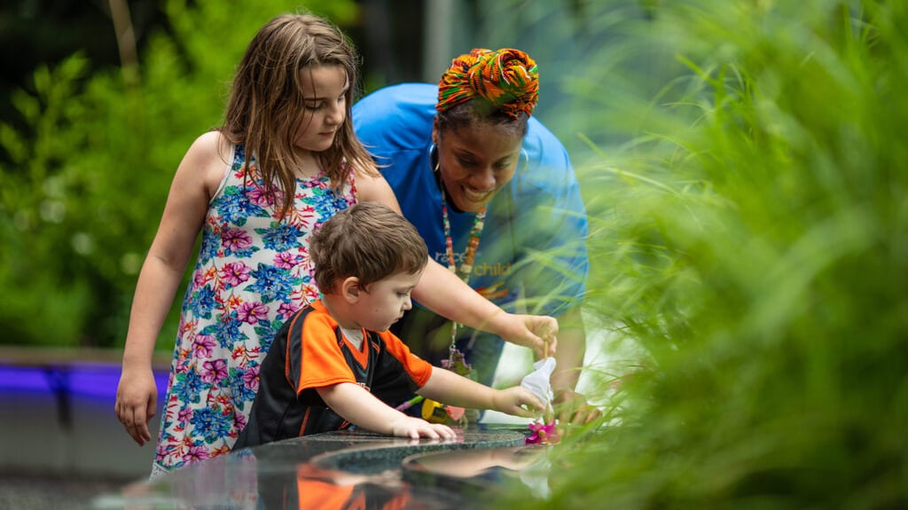 hospital staff plays with children in healing garden