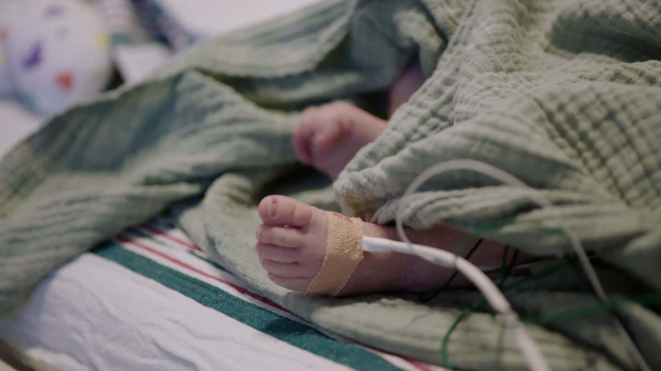 Tiny toes of a preemie peep out from under the covers in the NICU
