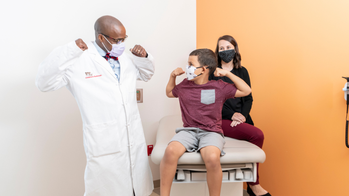 Doctor and young patient flexing their muscles in an exam room