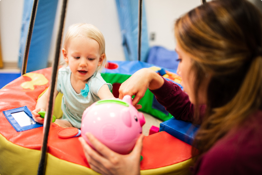 A child life specialist holds a toy and plays with a young patient