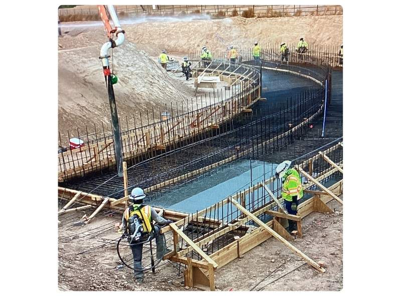 Construction workers standing in trench while completing a box culvert and U-channel segments