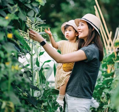 Mother and child exploring trees in a garden