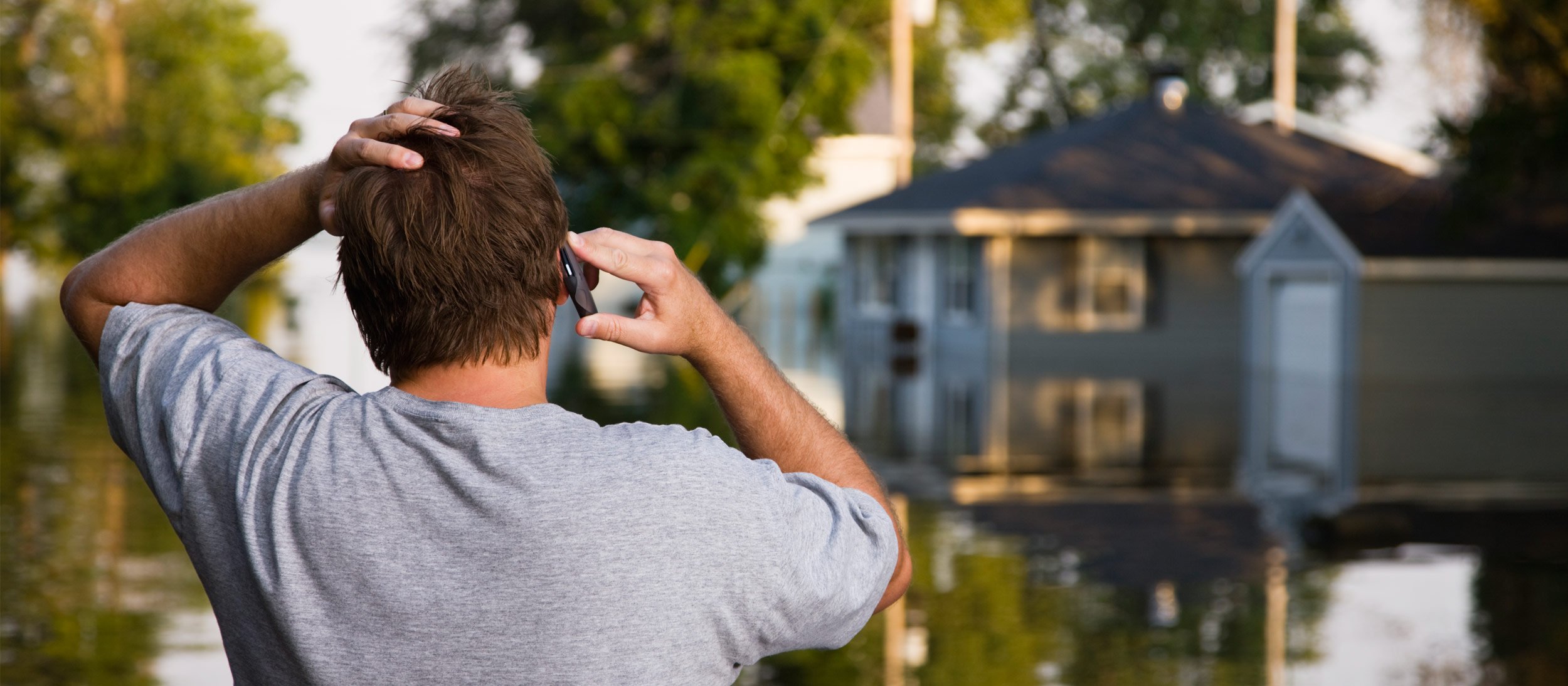 Man on a phone looking at flood waters