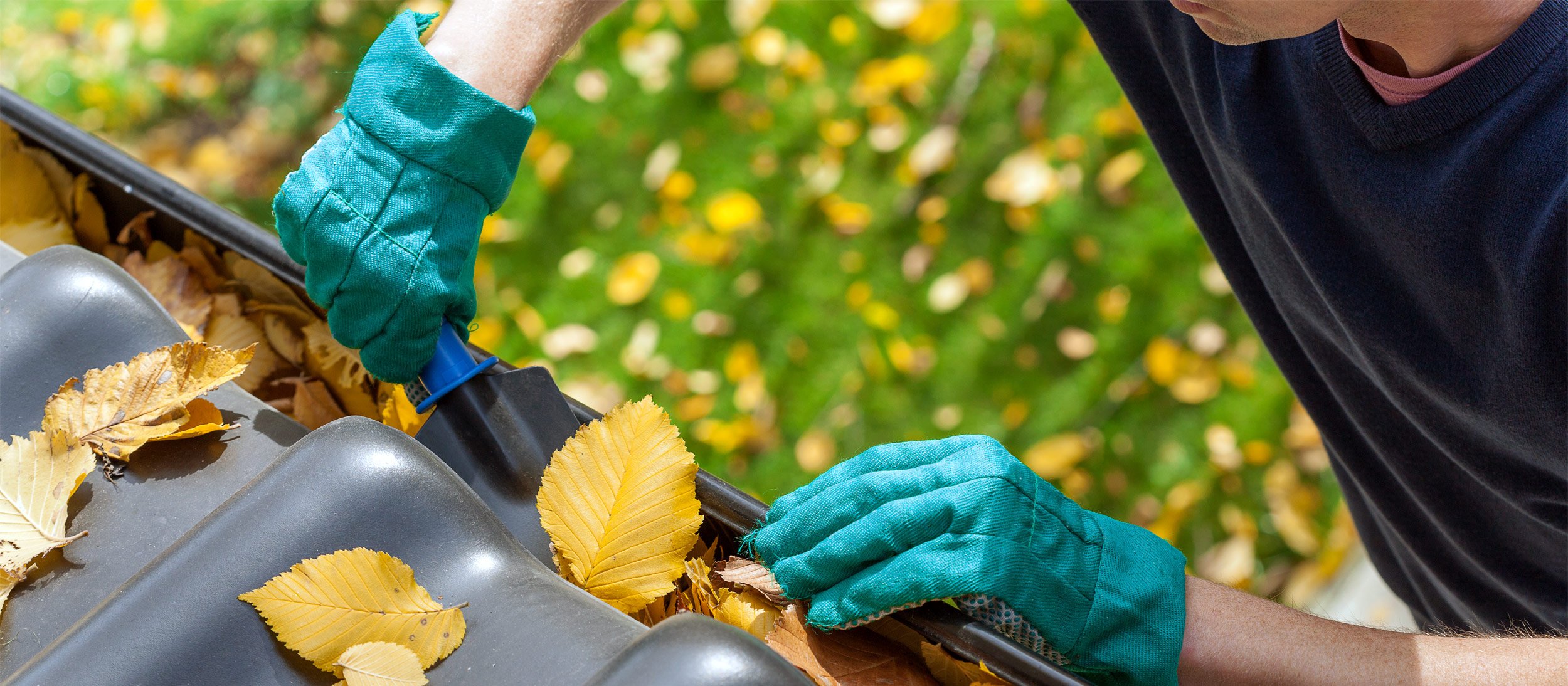 Using a trowel to clear leaves from gutters