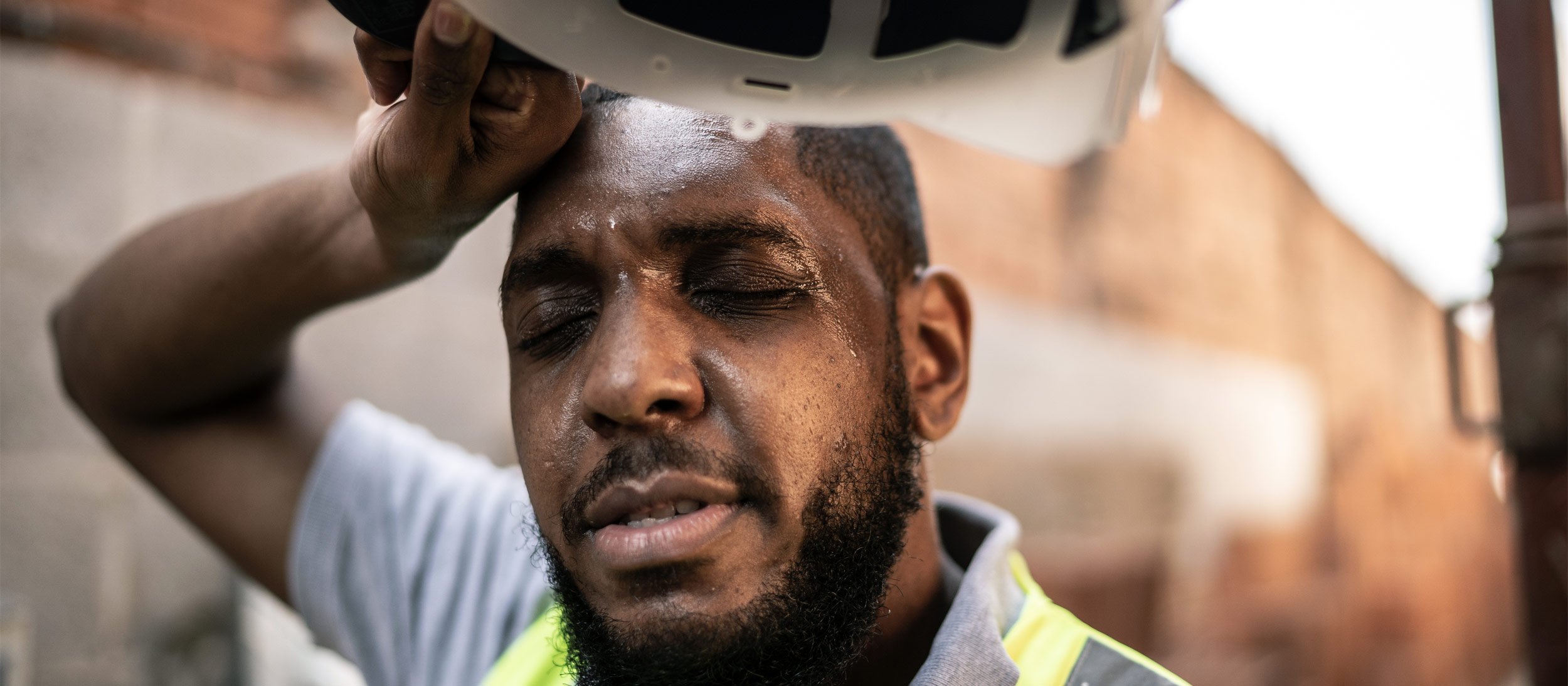 A construction worker wiping sweat from his brow with the back of his hand