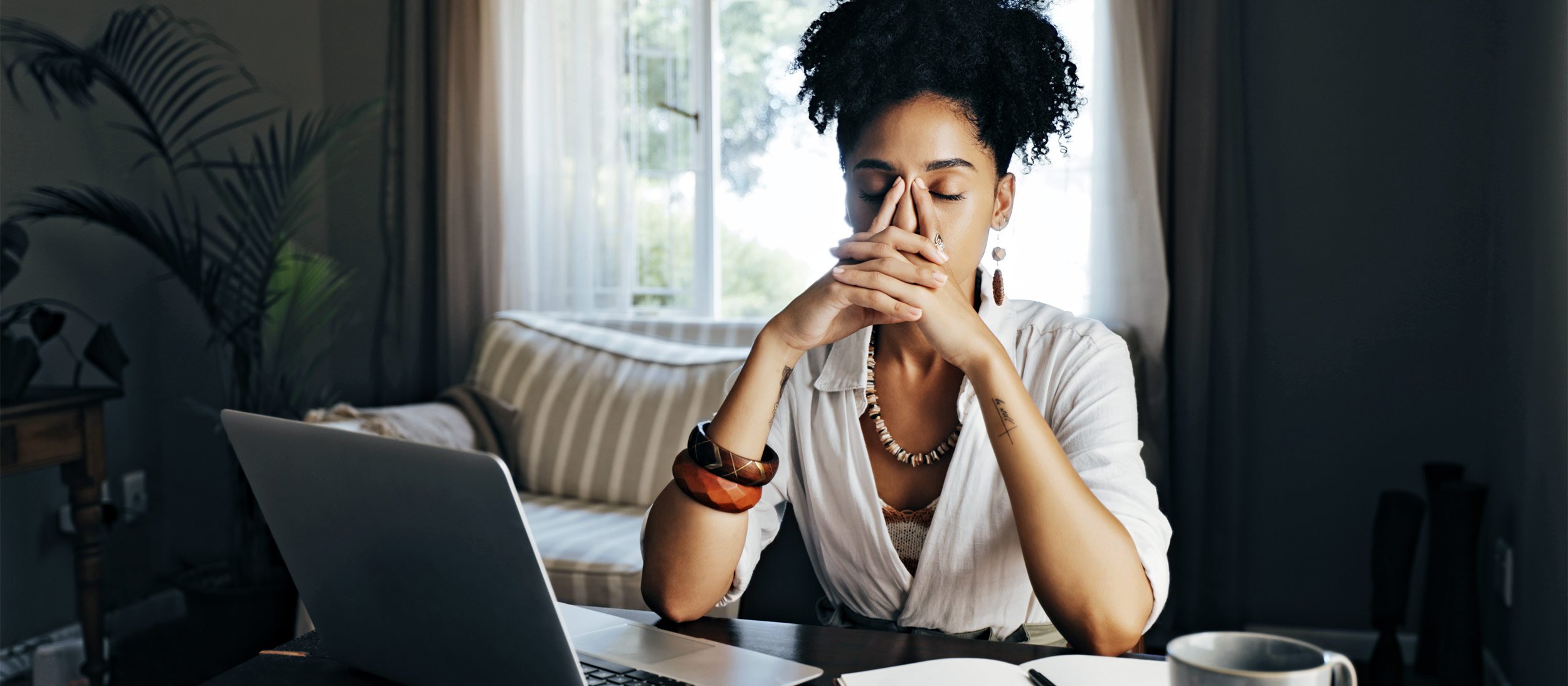 A young woman thinking in front of her laptop