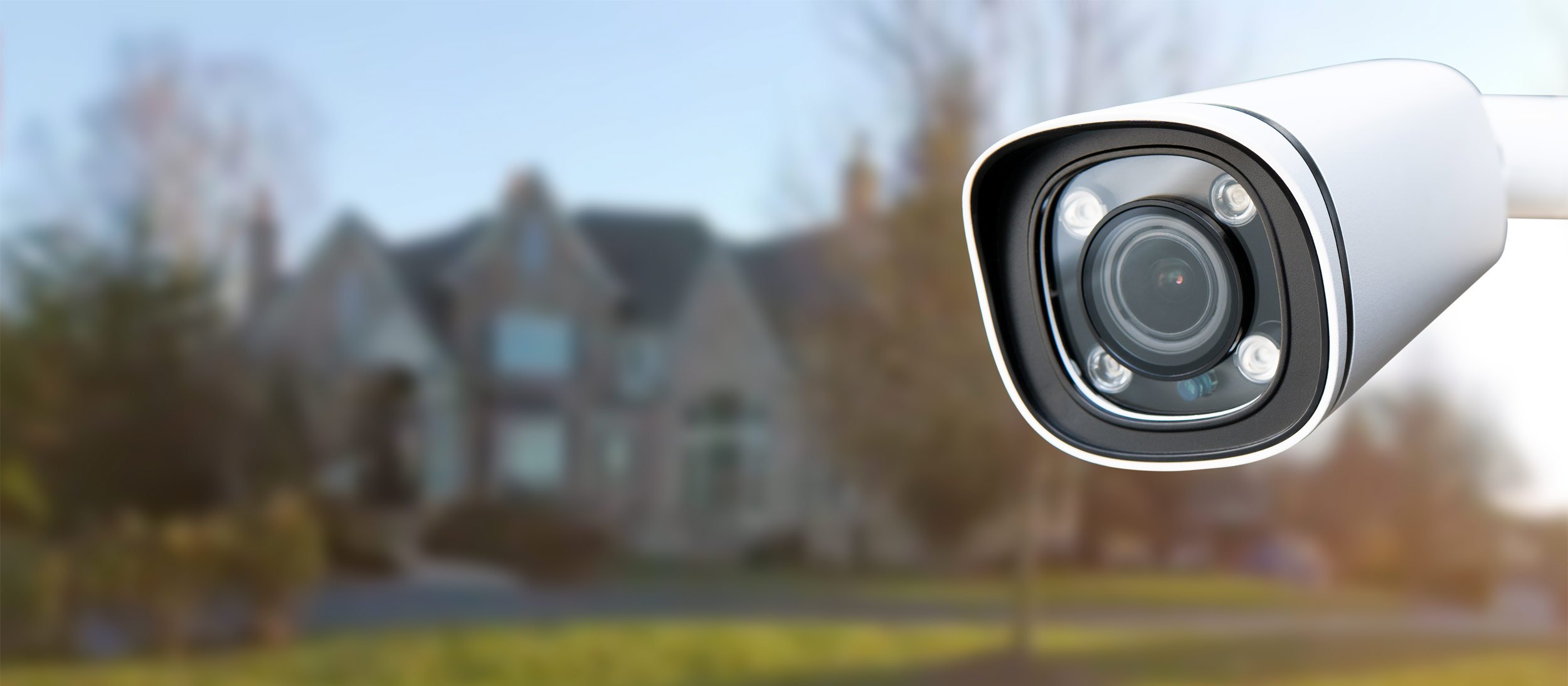A security camera with a house blurred in the background