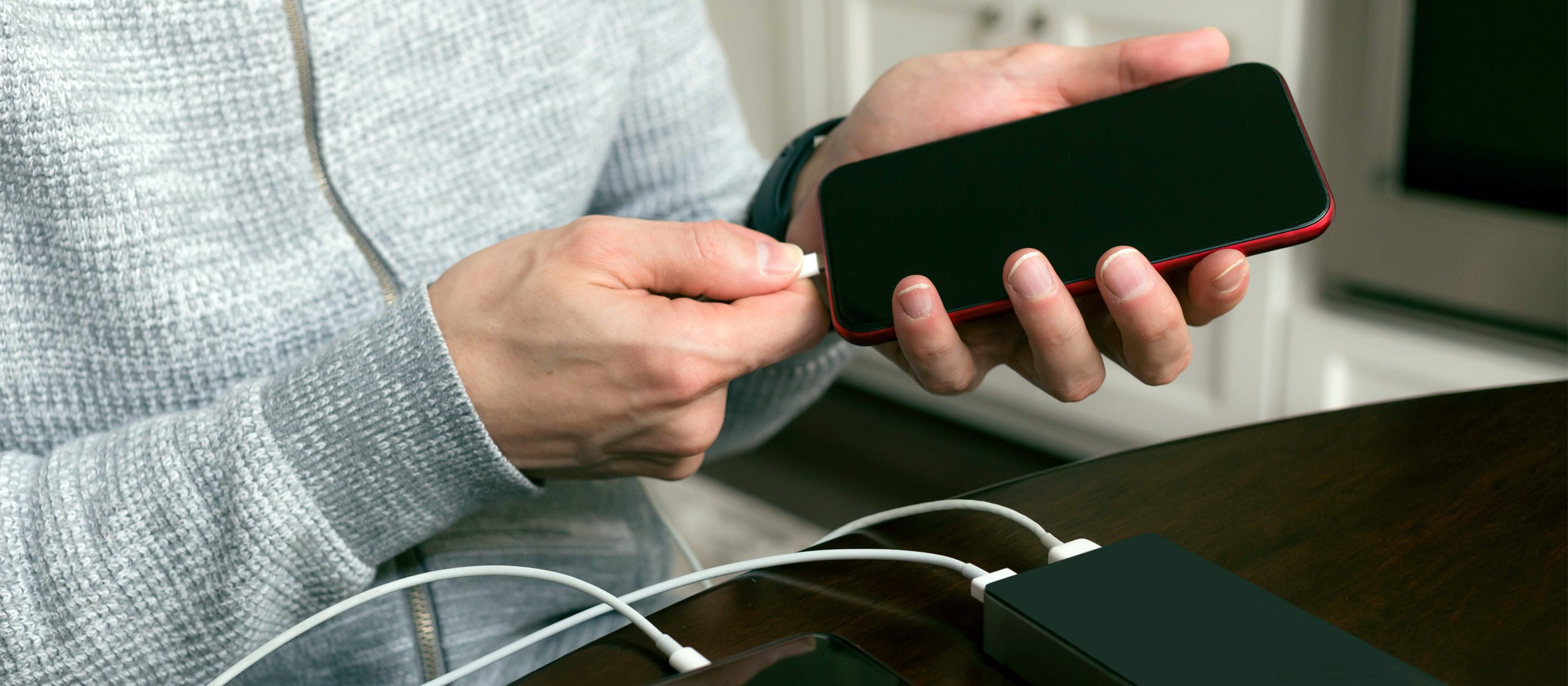 A person plugging a charging cable into their mobile device