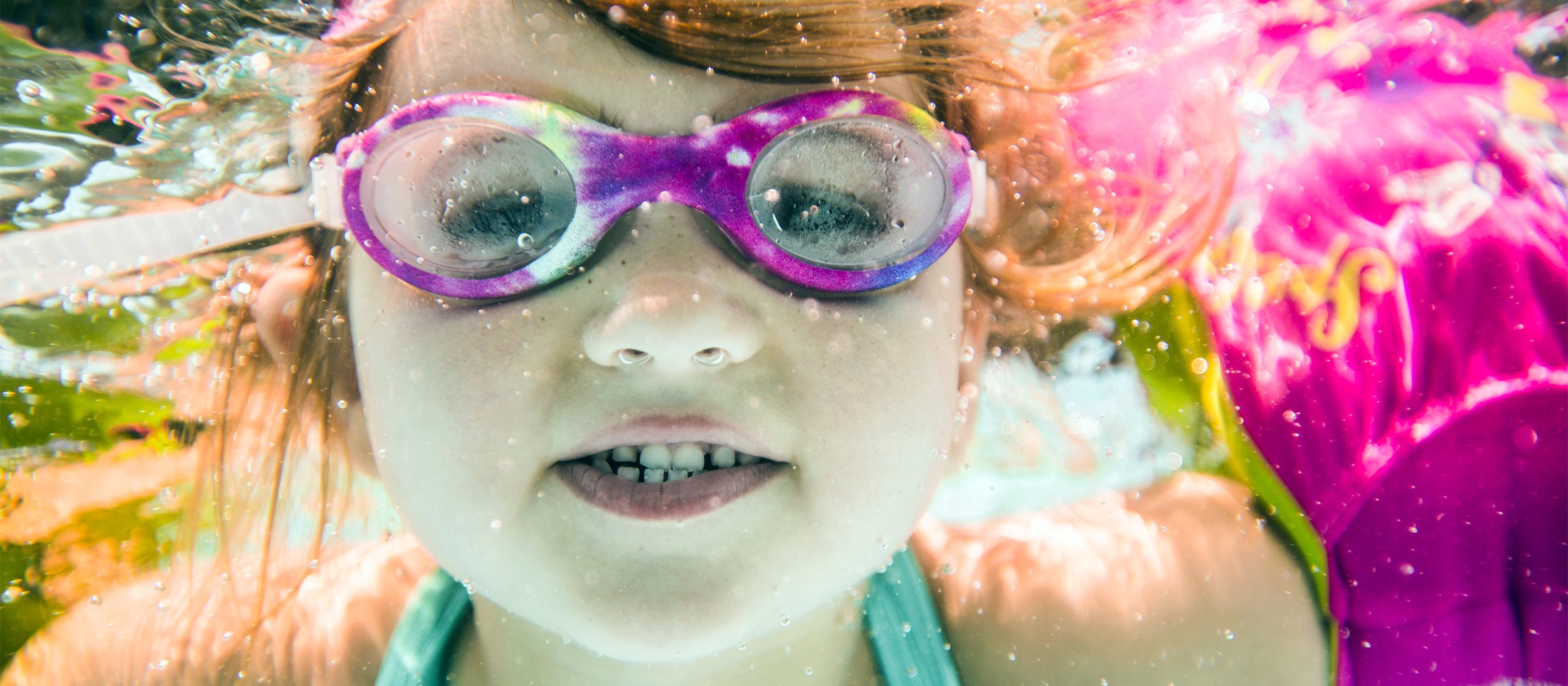 A girl with goggles swimming underwater