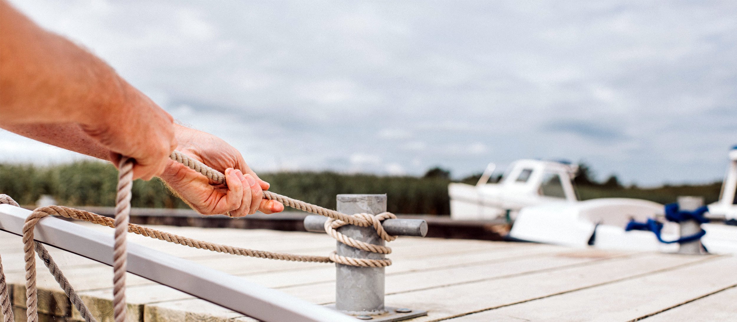 A person tying their boat to a dock to secure the watercraft
