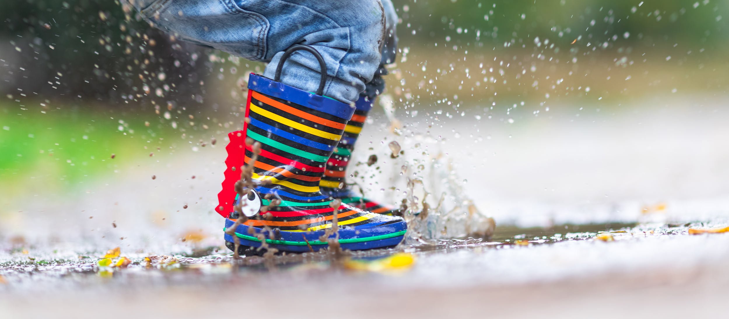 Child jumping in rain puddles