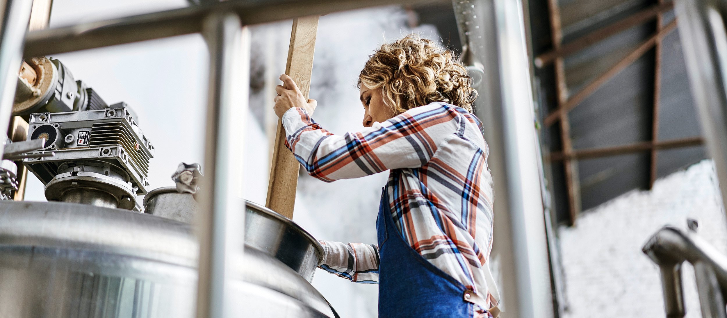 A brewer stirring a large vat