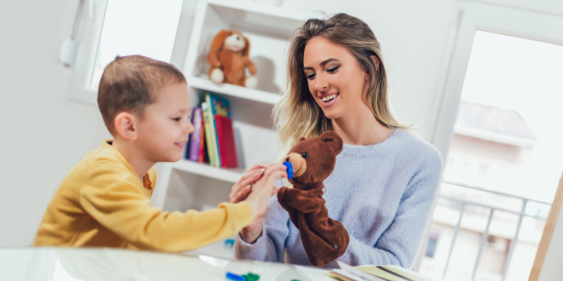 boy and woman play with puppet bear