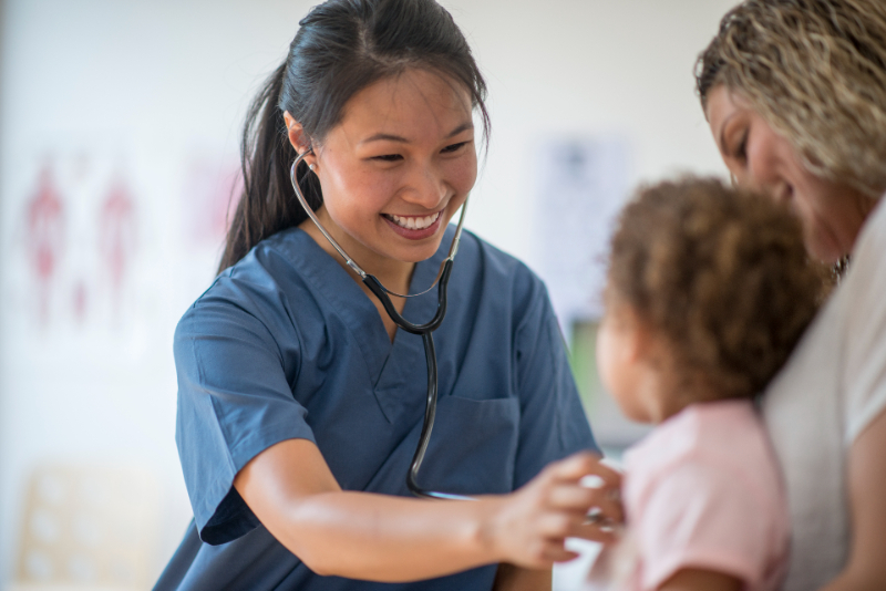 A nurse is listening to a little girl's heartbeat at a doctors appointment.