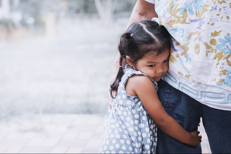 little girl clings to dad's leg