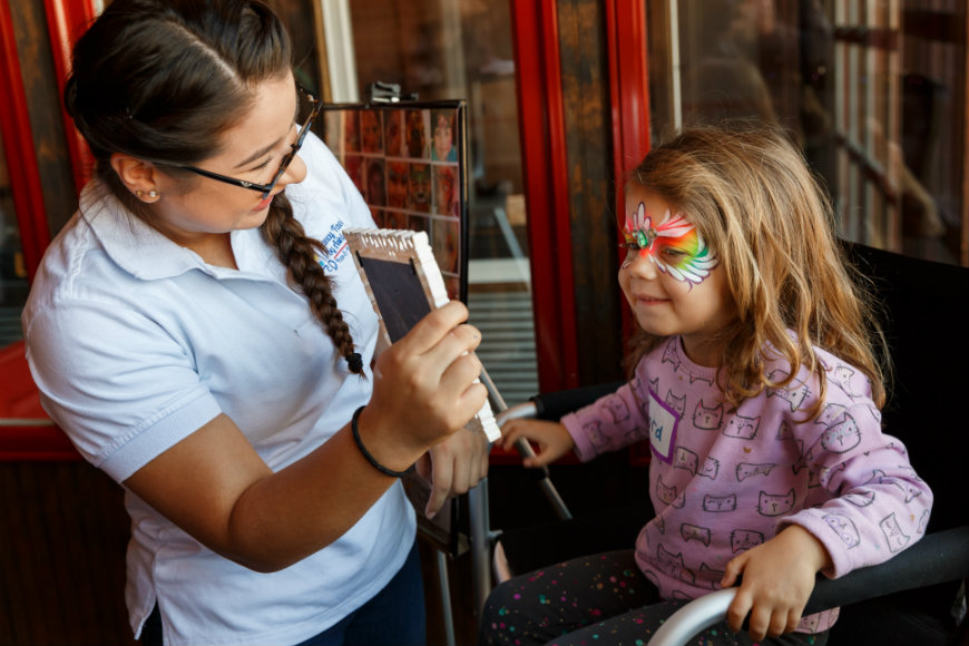 Little girl receives a face mask at craniofacial party and smiles.