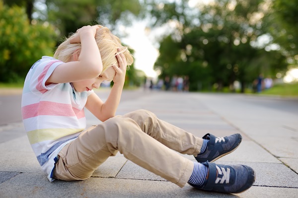 Picture of boy holding head sitting down