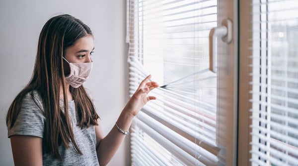 Girl wearing mask looks out window