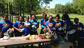 Children eating fruit and vegetables at a picnic table. 