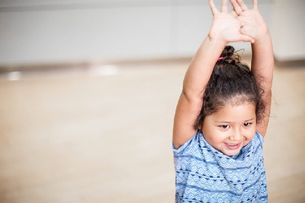 Young girl in blue shirt stretching her arms together in the air