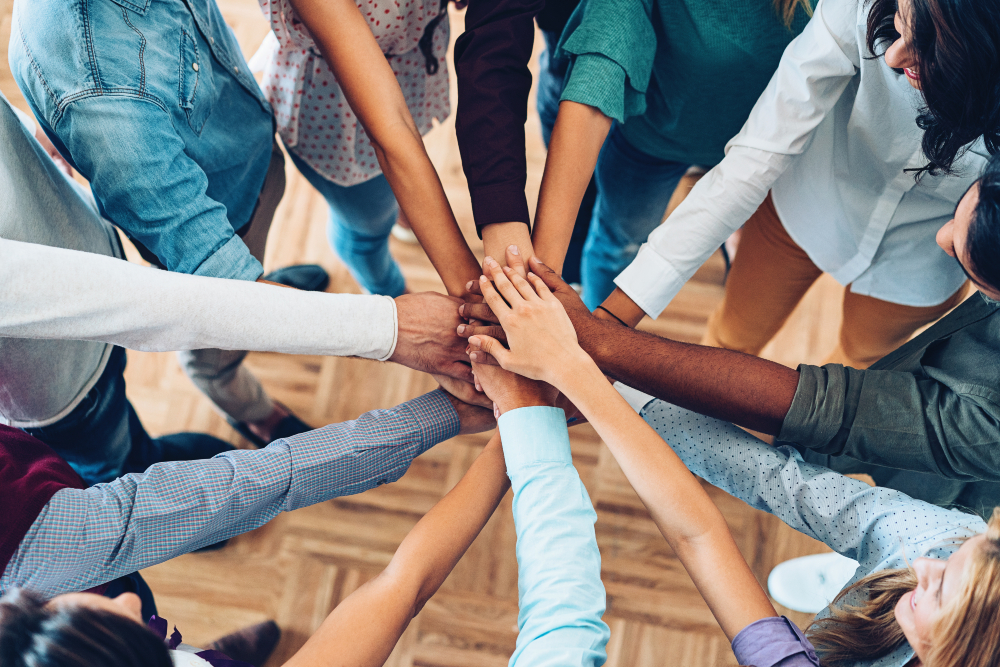 Group of individuals putting their hands in a circle