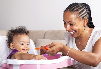 Mother feeding toddler sitting in a high chair