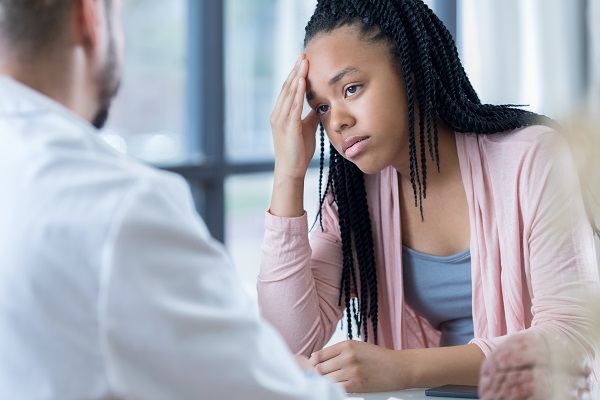 A girl holding her forehead at a medical consultation