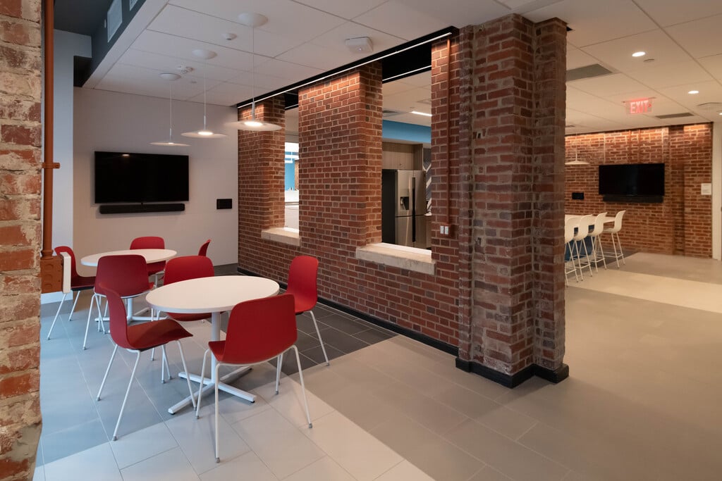 A sitting area with table, chairs and a television next to the kitchen.