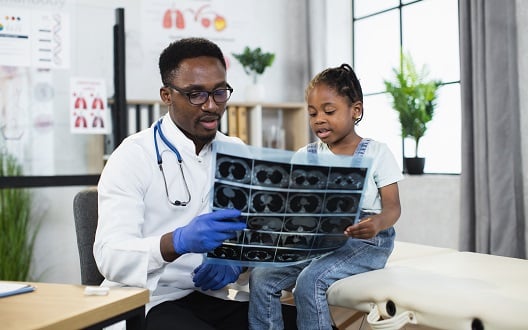 A doctor looks at an x-ray image with a young girl