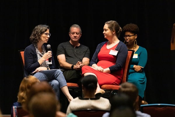 A woman in the audience asks a question during a presentation.