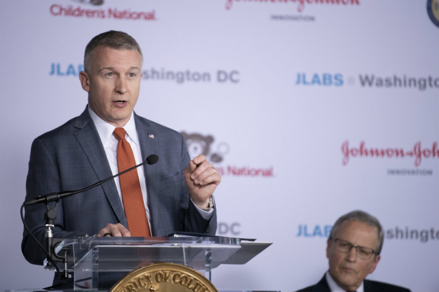 A man gestures with his hand while speaking at the podium.