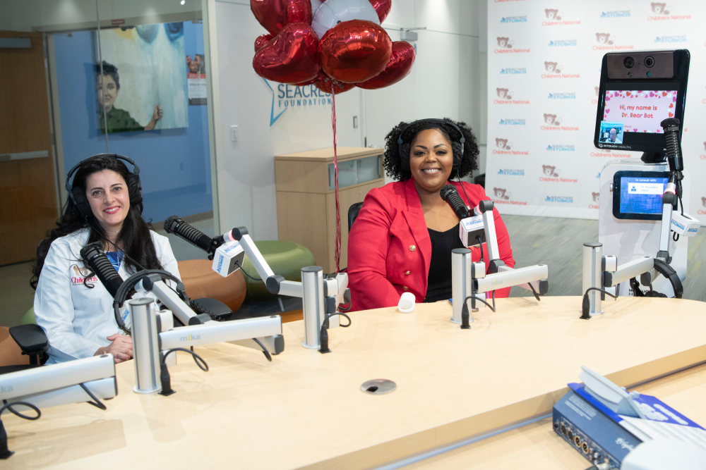 Dr. Atabaki and Monique Powell sitting down with red balloons and Dr. Bear Bot