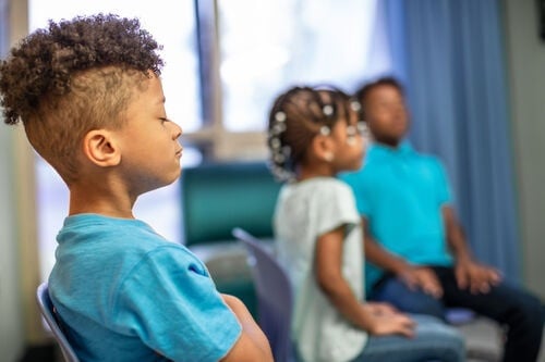 Kids sit with their eyes closed during a relaxation exercise