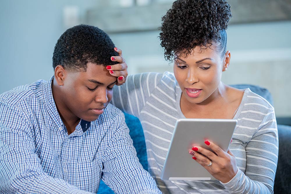 Mother checking the temperature of her teenage son's forehead