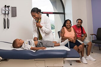 Doctor examining a toddler while parents look on