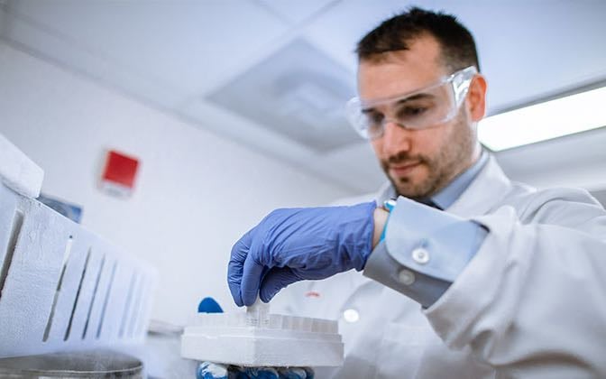 A White male scientist works in a laboratory.