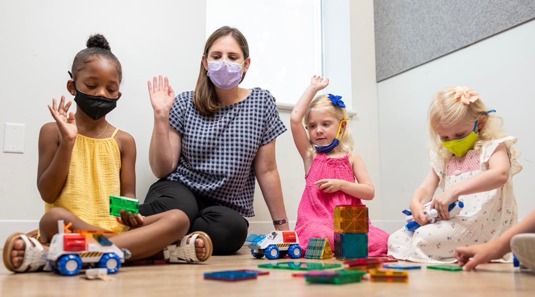 Three young female patients, one Black, two White work with a White female mental health practitioner.