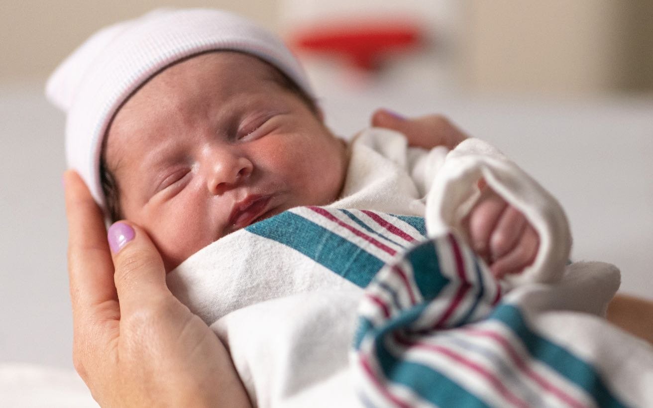 A newborn swaddled in a hospital blanket.