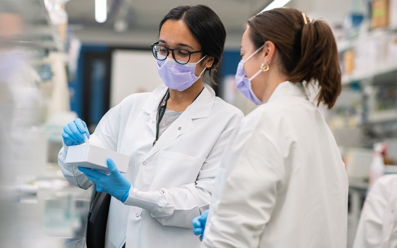 Two female researchers confer in the lab.