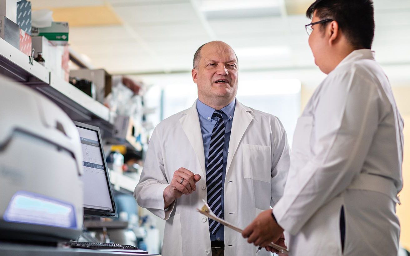 Two scientists, one male and one female, confer in the lab.