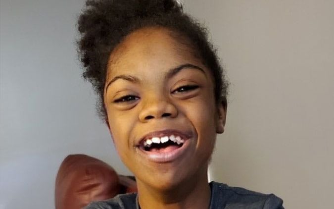 Close-up photo of a Black elementary school-aged female patient smiling.