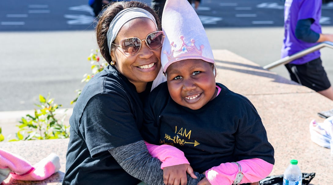 A Black mother and her daughter pose for a photo at a fundraiser event.