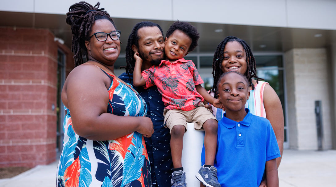 Portrait of a Black family with three children, two male and one female.