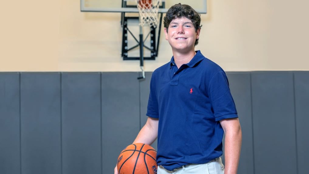Image of White teenaged patient posing for a portrait on a basketball court in a gymnasium.