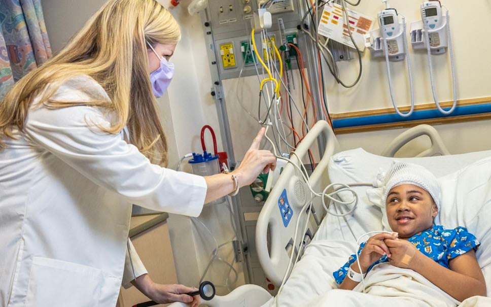 A Children's National health professional assesses a young brain tumor patient.