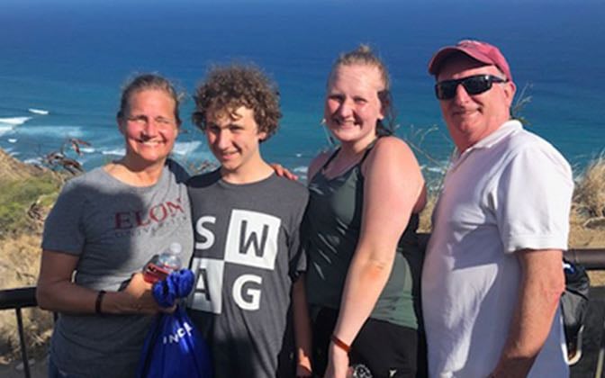 A family of four poses for a photo at the oceanside.