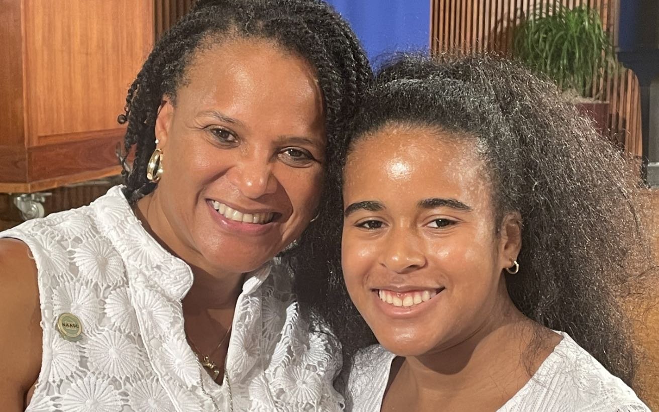Photo of a Black mother and her teenaged daughter. They are both smiling.