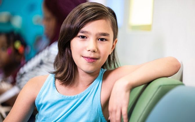 A pre-teen patient smiles at the camera.